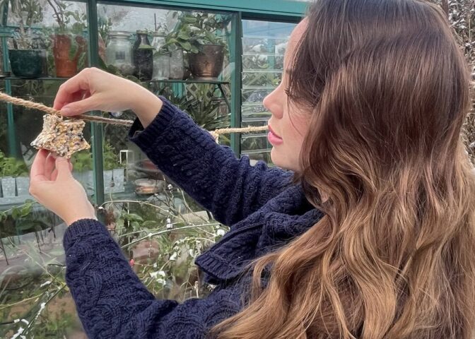 Anne Wieggers hangt een vogelslinger op in haar tuin.