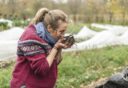 Esther houdt handen vol bokashicompost dichtbij haar gezicht om de geur te ruiken.