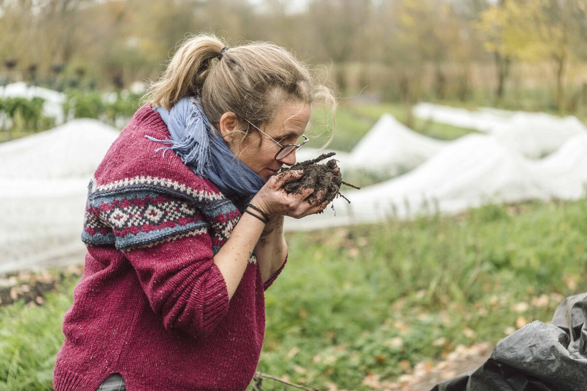 Esther houdt handen vol bokashicompost dichtbij haar gezicht om de geur te ruiken.